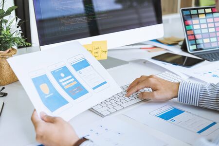 Cropped shot of startup UX UI front end designers developing programming and coding mobile application from prototype and wireframe layout. Mobile application developer workplace concept.の写真素材