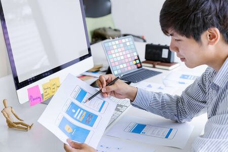 Cropped shot of creative UX UI designer developing programming and coding mobile application from prototype and wireframe layout. Mobile application developer workplace concept.の写真素材