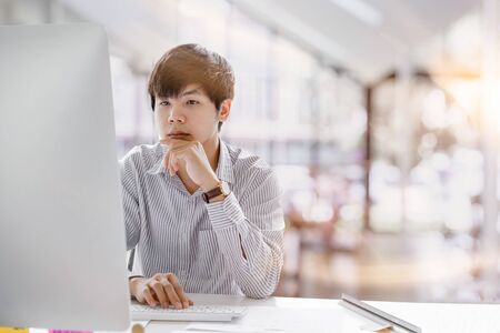 Cropped shot of a serious asian businessman thinking and concentrating typing on laptop at co-working spaces. Man laptop working conceptの写真素材