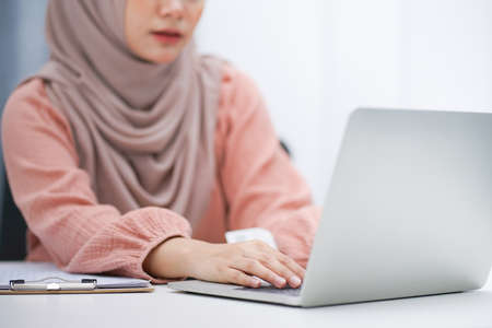 Cropped shot of asian muslim woman brown hijab working at her home.の写真素材