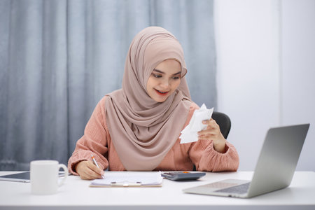Stressed muslim woman calculating monthly financial, plan budget on computer, pay bills or taxes online at home.の写真素材