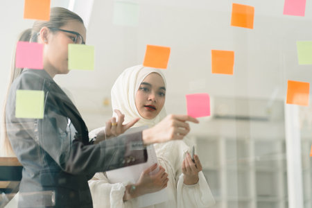 During a creative brainstorming process, business leaders are gathered in a boardroom, utilizing adhesive notes to exchange and enhance their ideas.の写真素材
