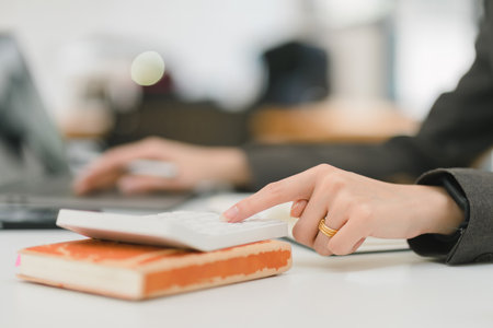 Close-up of an accountant working on a desk, using a calculator to prepare a financial report in an office.の写真素材