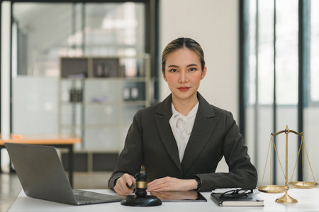 A businesswoman and lawyers are discussing contract papers with a brass scale on a desk in an office. The concepts of law, legal services, advice, justice, and real estate are being discussed.の写真素材