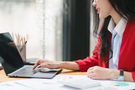 Crooped shot of a beautiful Asian businesswoman is using a digital laptop at her desk in a modern office.の写真素材