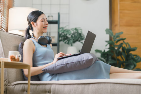 Happy young businesswoman is shown working on a laptop computer in her home office. The image represents the concept of working from home.の写真素材
