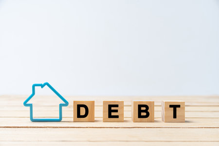 "DEBT" wood letter with blue house model on white background. Financial problems with home debt, money concept.の写真素材