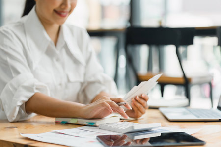 Businesswoman Calculating Financial Budget with Calculator and Laptop on Office Desk