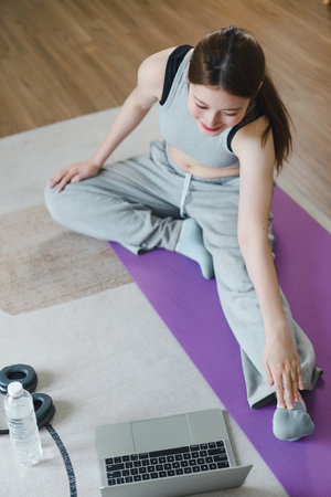 Asian young woman doing yoga stretching exercise on mat yoga, fitness exercises. Healthy lifestyle Calmness and relax at home.の写真素材