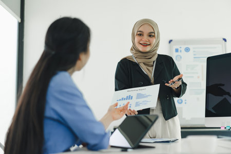 Two professional women discuss and analyze financial data and marketing strategies, presenting and brainstorming to increase company profitsの写真素材