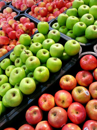 Green and red apples being sold in a market.の素材