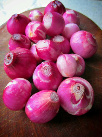 Peeled shallots on a chopping board.