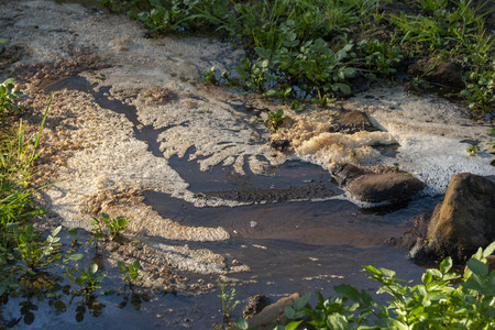A front view of foam scum floating on top of water in a flowing riverの写真素材
