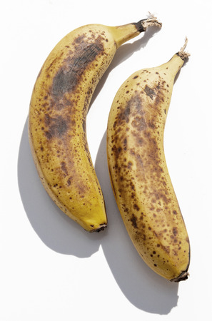 A close up view of two ripe yellow bananas next to each other on a isolated white backgroundの写真素材