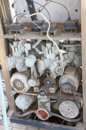 A close up view of the inside of the engene and elecrtrical wiring of a old rusted petrol pumpの写真素材