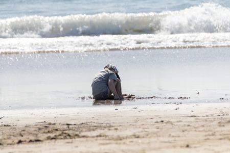 A close up view of a young boy playing in the water and sand on durban beach front on a sunny...