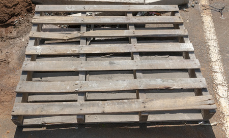 A close up view of a old broken wooden pallet in a parking lot on a construction site