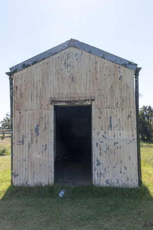 A close up front view of a old rusted run down metal barn or storage unit at a old railway staionの写真素材