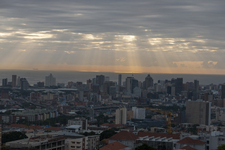 A view of the suns rays shining through the clouds onto the calm ocean water on a warm summers morningの写真素材