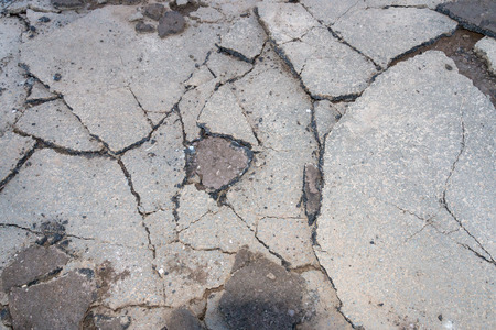 A close up view of an old driveway where the tar has been broken up into differant size pieces so that new tar can be layed.の写真素材