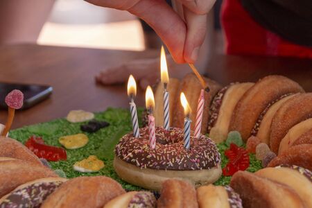 A close up view of five pink and blue candels being lite on a doughnut cake
