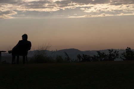 A close up view of the early morning sun rise, with the silhouette of someone looking out into the valley.のeditorial素材