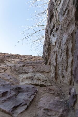 A close up view of the sky from the bottom of a stone wallの写真素材