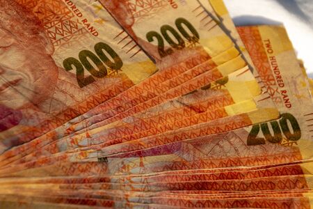 A close up view of two hundred south african notes in a pile on a isolated black backgroundの写真素材