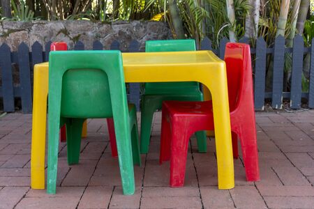 A close up side view of a colourful plastic kids table and chairs on the brick playgroundの写真素材