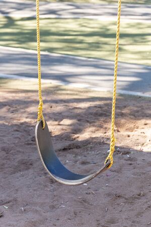 A close up view of the bottom half of childerns rubber swing in a sand pit play groundの写真素材