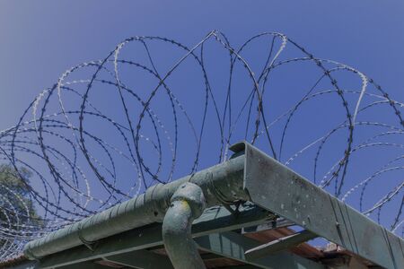 A close up view of large metal barbed wire on top of a old buildings roofの写真素材