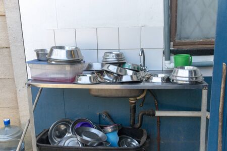 A close up view of metal dogs dishes piled up on a washing sink waiting to be cleanedの写真素材