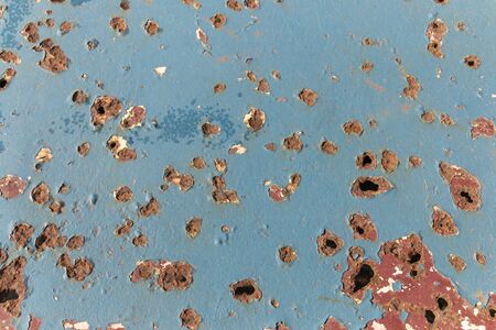 A close up view of a metal table with lots of rusted holes all over itの写真素材
