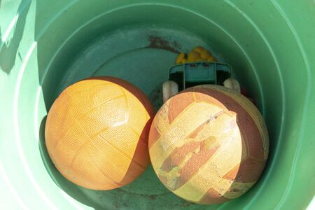 A close up view of rugby, soccor balls in a orange plastic bucketの写真素材