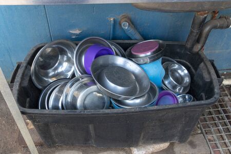 A close up view of metal dogs dishes piled up in a plastic black bucketの写真素材