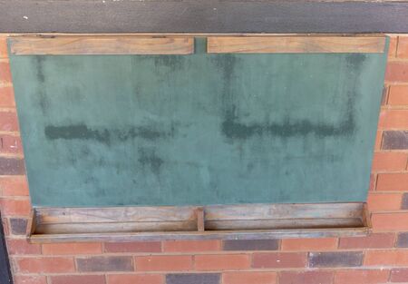 a close up view of a old green chalk board with wooden trime on a brick wallの写真素材