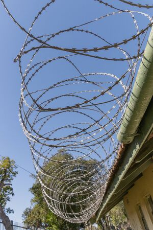 A close up view of large metal barbed wire on top of a old buildings roofの写真素材