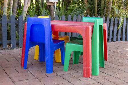 A close up side view of a colourful plastic kids table and chairs on the brick playgroundの写真素材
