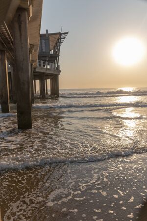 A close up view of the ocean water coming up through the pillers holding up the pierの写真素材
