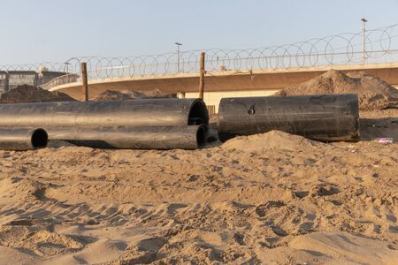 A close up view of large black rubber pipes waiting to be layed into the sandの写真素材