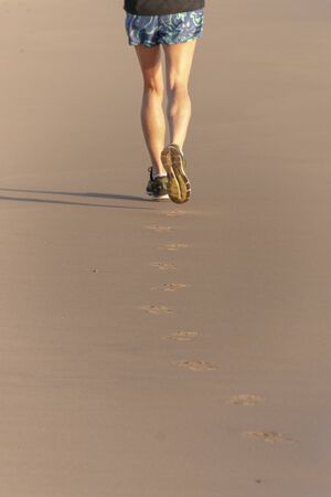 A close up back view of a women runner do her morning run on the beachの写真素材