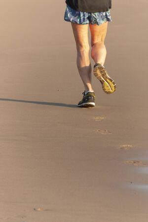 A close up back view of a women runner do her morning run on the beachの写真素材