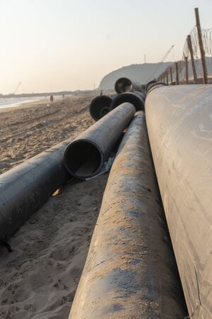 A close up view of large black rubber pipes waiting tobe layed into the sandの写真素材
