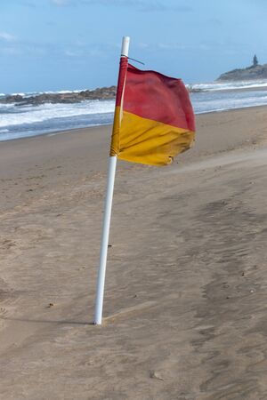 A close up view of a flag pole on the beach to show the designated swimmimg areas on a very windy dayの写真素材