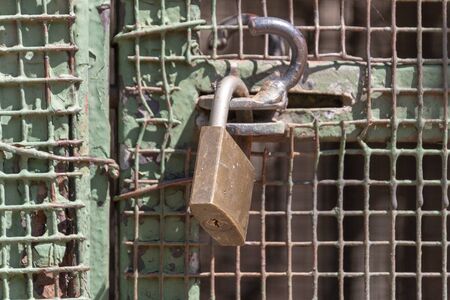 A close up view of a padlock keeping a metal gate closedの写真素材