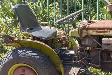 A close up view of a small old rusted tractor sitting on the hot sunの写真素材