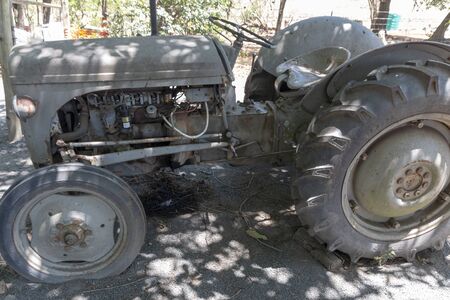 Durban-South Africa, November 2019- A close up view of old rusted tractor with a flat front tyre sitting in the field on a farmの写真素材