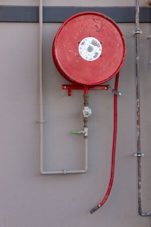 A close up view of a red fire hose mounted on the wall for emergency's の写真素材