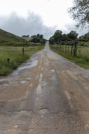 A close up view of a old contry road running though the fileds where the tar has deteareated. の写真素材