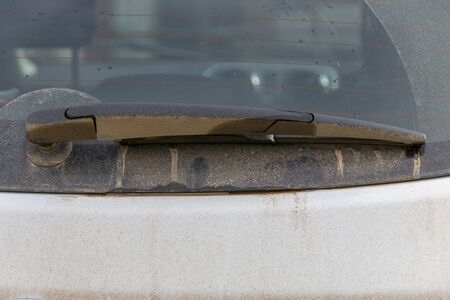 a close up view of the back of a car window with mud covering the windscreen wiper の写真素材